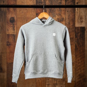 Op de afbeelding: Een grijs gemêleerd hoodie met een klein wit logo op de voorkant. De hoodie heeft een kangoeroezak en een capuchon met trekkoord.