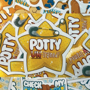 May include: A collection of colorful stickers featuring a teddy bear with a patch and the text "Plush Lover", a star-shaped sticker with the text "Potty Un-Trained!" and a blue and yellow sticker with the text "Check My Stats!" and a potty chart.
