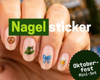 Op de afbeelding: Nagelstickers met Oktoberfest-thema's, waaronder een bruine krakeling, een groene hoed met een veer, een blauw-witte geruite strik en een bierpul. De tekst Nagel sticker en Oktoberfest Mini-Set is zichtbaar op de afbeelding.