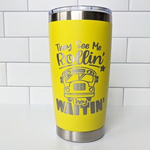 May include: Yellow stainless steel tumbler with a silver inscription that reads "They See Me Rollin' They Waitin'" with a cartoon school bus graphic.