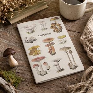 May include: A rectangular notebook with a cream-colored cover featuring various detailed illustrations of mushrooms in shades of brown, yellow, and red. The word NOTEBOOK is printed in black capital letters in the center of the cover.