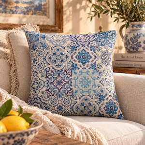 Puede incluir: Un cojín cuadrado con un patrón de patchwork en azul y blanco que presenta intrincados diseños florales y geométricos de azulejos. La tela muestra una variedad de motivos repetitivos en tonos azul marino, azul real y azul claro sobre fondo crema.