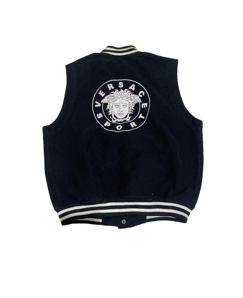 May include: Black sleeveless varsity jacket with a white embroidered Versace Sport logo on the back. The logo features a white Medusa head inside a circle.