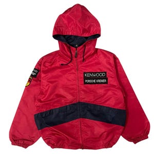 May include: A red and black hooded jacket with a zipper closure. The jacket has a Kenwood Porsche Kremer logo on the front.