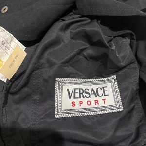 May include: Black jacket with a white and black Versace Sport label on the pocket.