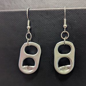 May include: A pair of silver earrings made from the pull tabs of aluminum beverage cans. The earrings are attached to silver hooks.