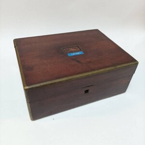 May include: A dark brown wooden box with a brass trim and a blue label that says "LOT 881".