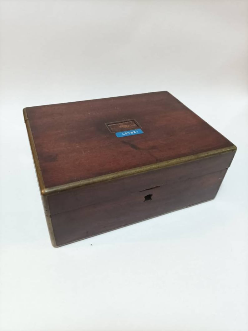 May include: A dark brown wooden box with a brass trim and a blue label that says "LOT 881".