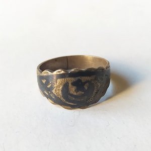 Könnte beinhalten: Ein goldener Ring mit einem schwarzen Emaille-Design, das eine Mondsichel und einen Stern zeigt.