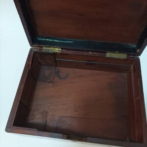 May include: An empty wooden box with a hinged lid. The box is made of dark wood and has a simple design.