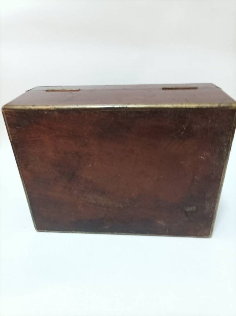 May include: A dark brown wooden box with brass accents. The box has a hinged lid and is closed.