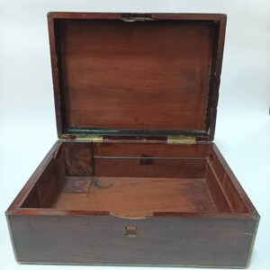 May include: An empty wooden box with brass hinges and trim. The box is open and the inside is visible. The box is made of dark wood and has a smooth finish.