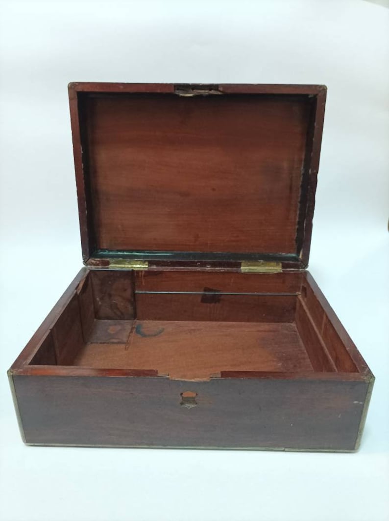 May include: An empty wooden box with brass hinges and trim. The box is open and the inside is visible. The box is made of dark wood and has a smooth finish.