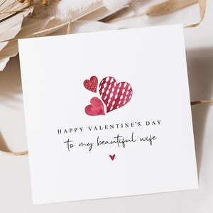 May include: A white Valentine's Day card with three red hearts. The card reads "HAPPY VALENTINE'S DAY" and "to my beautiful wife" in elegant script. A small red heart is at the bottom.
