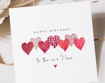 May include: A white card with the text "Happy Birthday" and "To the one I love" in black script. The card is decorated with a row of six red watercolor hearts with different patterns.