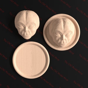 Puede incluir: Tres tallas de madera de un rostro extraterrestre. Una talla es una placa circular plana, otra es una placa circular plana con un borde elevado, y la tercera es una talla plana tridimensional.