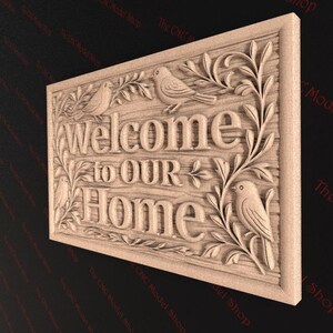 May include: A wooden sign with the words "Welcome to OUR Home" carved into it. The sign features detailed relief carvings of birds and foliage. The sign is rectangular and has a light brown color.