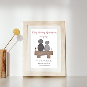 May include: A framed print celebrating a ruby wedding anniversary with a stone couple sitting on a bench. The text reads "Ruby Wedding Anniversary 40 years", "20.06.1983", "Mark & Julie", and "And the adventure continues 2023".