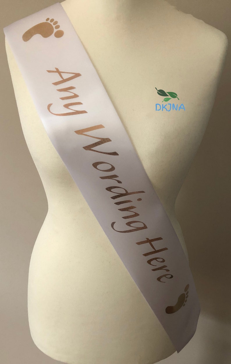 May include: White satin sash with gold foil footprints and the text "Any Wording Here" printed on it.