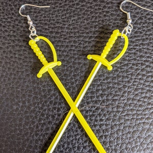 May include: A pair of yellow plastic sword earrings. The swords are crossed and have silver hooks.