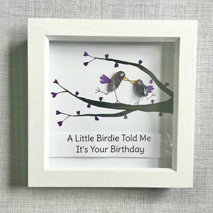 Peut inclure: Une image encadrée blanche avec une illustration en noir et blanc de deux oiseaux sur une branche avec des cœurs violets. Le texte dit "A Little Birdie Told Me It's Your Birthday."