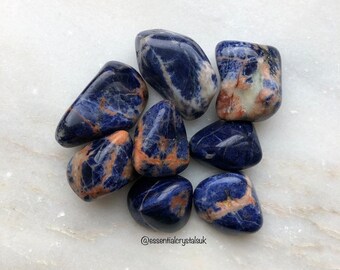 May include: A collection of eight tumbled blue and orange Sodalite stones. The stones are smooth and polished, with a variety of patterns and colors.