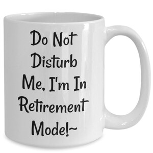 Pode incluir: Caneca de café de cerâmica branca com texto preto que diz "Não perturbe, estou no modo aposentadoria!"