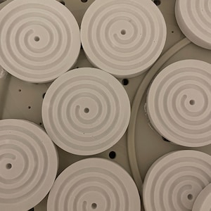 Könnte beinhalten: Ein Set aus drei Keramikbechern mit gesprenkelter, matter Oberfläche. Die Becher sind in den Farbtönen Creme, Hellgrau und Dunkelgrau gehalten. Jeder Becher hat ein schlichtes, minimalistisches Design und einen abgerundeten Henkel.