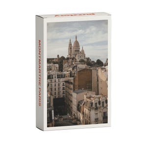 Könnte beinhalten: Eine Postkarte mit einem Foto der Sacré-Cœur-Basilika in Montmartre, Paris, Frankreich. Die Basilika ist eine weiße, kuppelförmige Kirche mit einem hohen Turm. Die Postkarte trägt den Text "MONTMARTRE PARIS" auf der Seite.