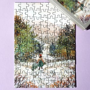 May include: A completed jigsaw puzzle showing a winter landscape with a person carrying greenery. The puzzle is mostly assembled, with some pieces missing. A box with the same image is in the upper right corner.