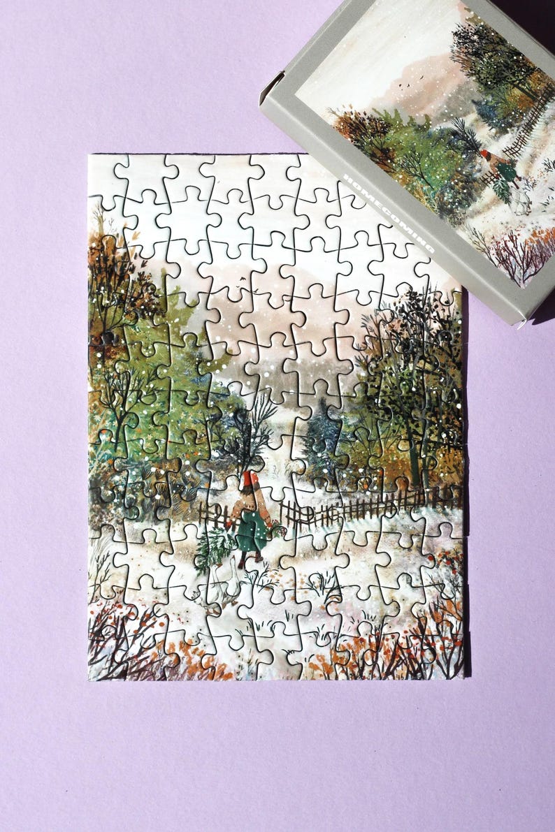 May include: A completed jigsaw puzzle showing a winter landscape with a person carrying greenery. The puzzle is mostly assembled, with some pieces missing. A box with the same image is in the upper right corner.