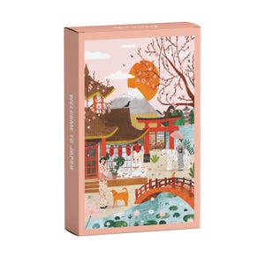 Könnte beinhalten: Eine rechteckige Puzzleschachtel mit rosa Rand zeigt eine japanische Landschaft mit Berg, Kirschblüten, rotem Torii-Tor, Brücke über einem Teich, einer Person im Kimono, einem weißen Tiger und dem Text WELCOME TO JAPAN.