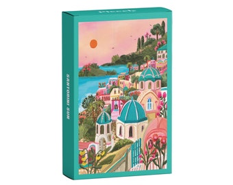 May include: A teal box with the words "Santorini Sun" printed on the side. The box features a colorful illustration of a seaside town with white buildings, blue domes, and a sunset in the background.