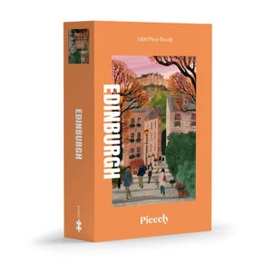 May include: A rectangular orange box for a 1000 piece puzzle titled Edinburgh. The front features an illustration of a street scene with people walking, stone buildings, trees, and a castle in the distance. The text Edinburgh and Piecely are visible.
