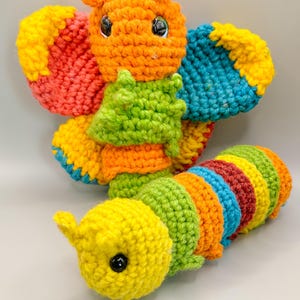 May include: A colorful crocheted butterfly and caterpillar toy set. The butterfly has orange, red, yellow, blue, and green colors. The caterpillar has yellow, green, orange, blue, and red stripes.