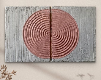 May include: A rectangular wall art piece featuring a textured gray background with a large, split circular motif in dusty pink. The pink circle is composed of concentric, raised ridges, and the text SenecaAvenueArts by Molly Dexter is visible.