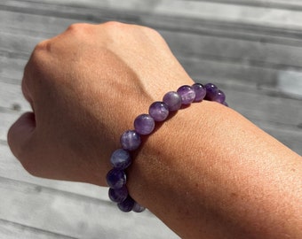 Puede incluir: Un brazalete de piedras preciosas de amatista púrpura con cuentas redondas.