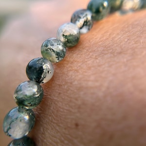 May include: A green and white agate beaded bracelet, with a close-up view of the beads.