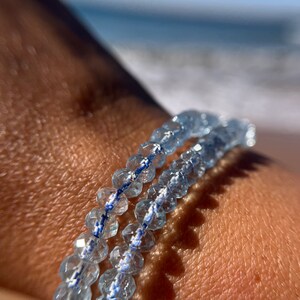 May include: A bracelet made of light blue faceted beads with a white and blue thread running through the beads.