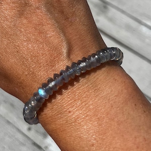 May include: A gray beaded bracelet with iridescent blue and green stones.