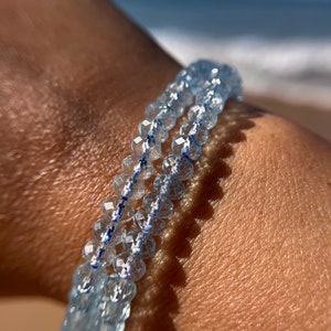 May include: A double-strand bracelet made of light blue faceted beads. The beads are strung on a clear elastic cord.