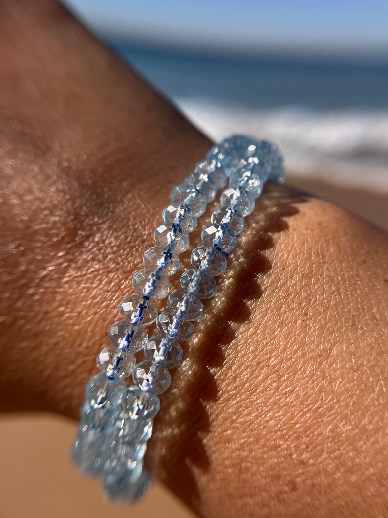 May include: A double-strand bracelet made of light blue faceted beads. The beads are strung on a clear elastic cord.