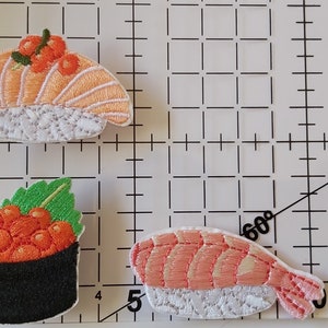 May include: Three embroidered sushi patches. One is salmon, one is shrimp, and one is a bowl of salmon roe.