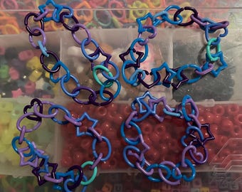 May include: Four colorful plastic bracelets made of interlocking star and heart shapes. The bracelets are blue, purple, and teal.
