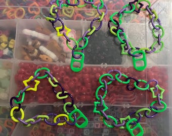 May include: Three colorful plastic chain necklaces with star and ring charms. The chains are green, purple, and yellow.