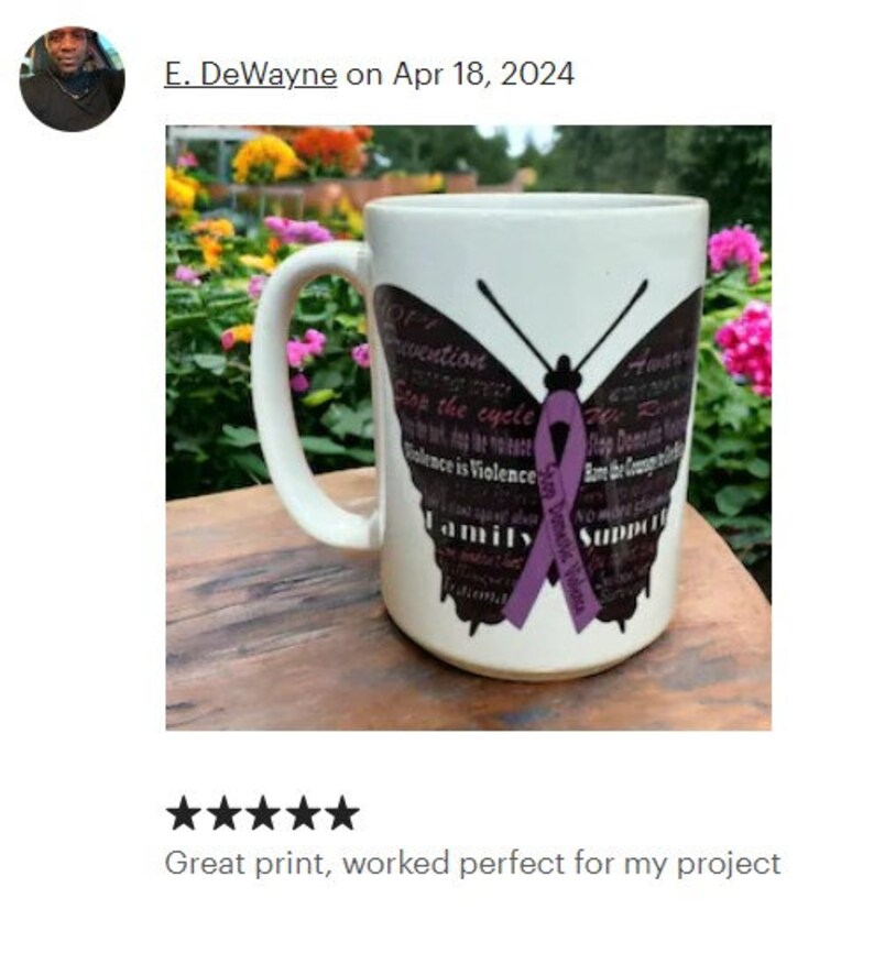 May include: White ceramic mug with a purple butterfly design. The butterfly has the words "Stop the cycle" and "Family Support" printed on its wings. The mug is on a wooden surface.