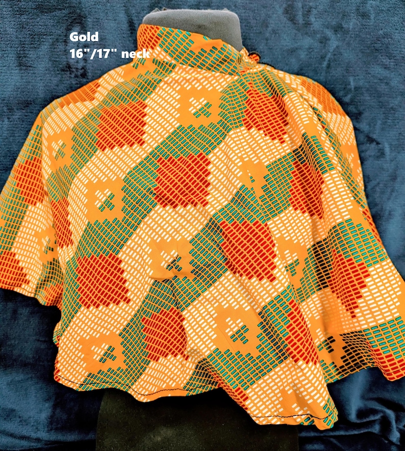 Puede incluir: Una blusa dorada con un estampado geom&eacute;trico en naranja, rojo, verde y blanco. La blusa tiene cuello alto y mangas cortas. El texto "Gold 16"/17" neck" es visible.