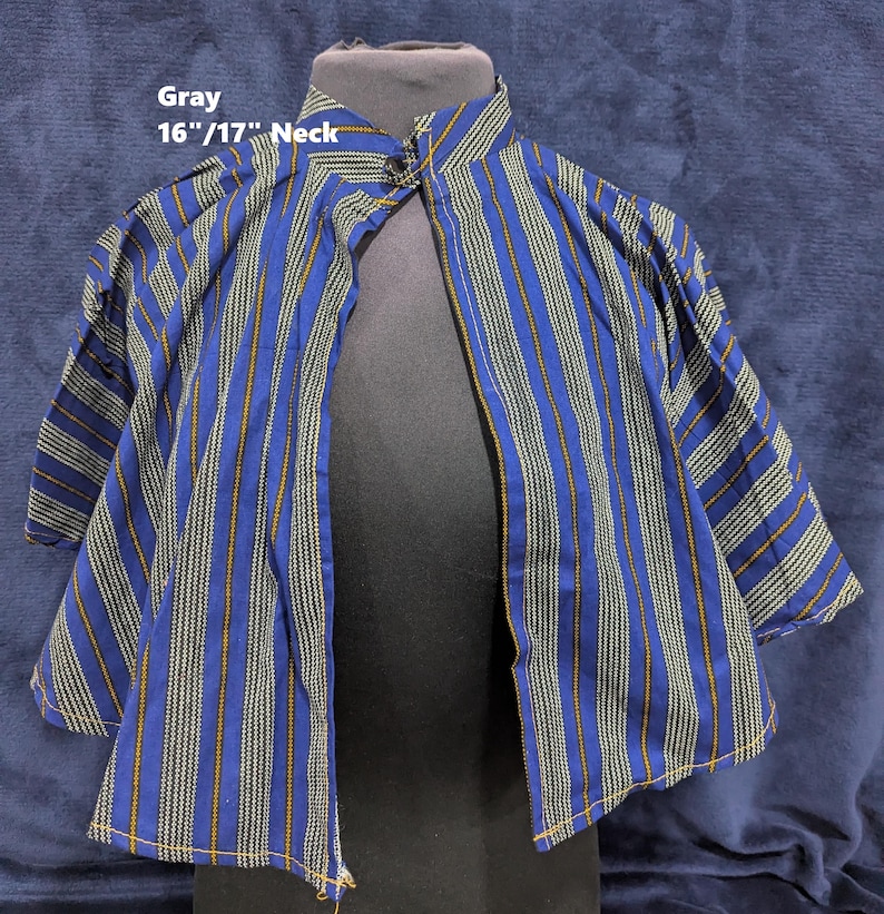 Puede incluir: Una camisa a rayas azules y blancas con cuello mandar&iacute;n. La camisa presenta rayas verticales en azul, blanco y dorado. El texto "Gray 16"/17" Neck" es visible en la imagen.