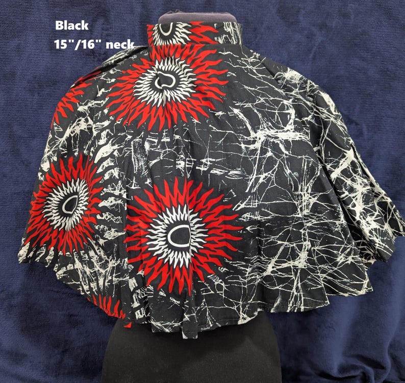 Puede incluir: Capa negra con cuello de 38 cm/41 cm, con un llamativo dise&ntilde;o de soles rojos y blancos sobre fondo negro. La capa tiene un cuello alto y una silueta acampanada.