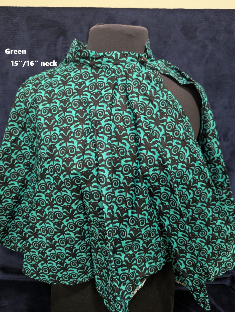 Puede incluir: Capa verde estampada con cuello alto, exhibida en un maniqu&iacute;. La tela presenta un dise&ntilde;o negro y verde azulado. El texto "Green" y "15"/16" neck" son visibles. Un accesorio de moda &uacute;nico.